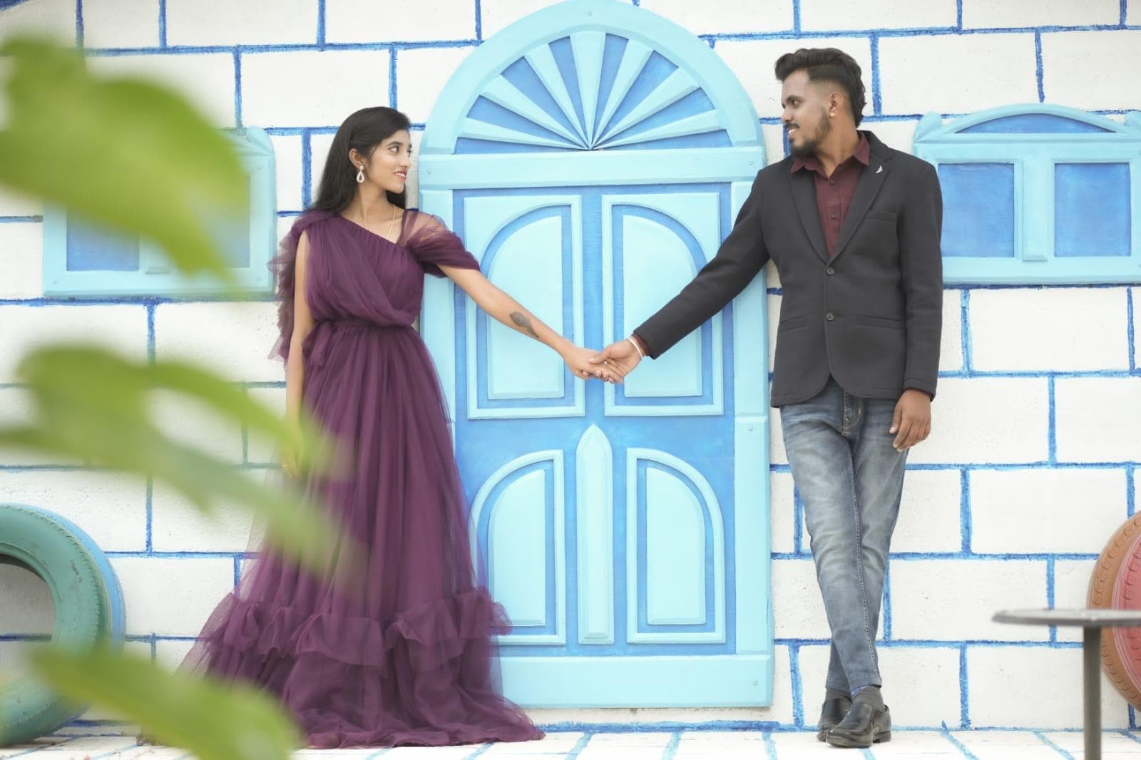 A couple holding hands before the blue arched door