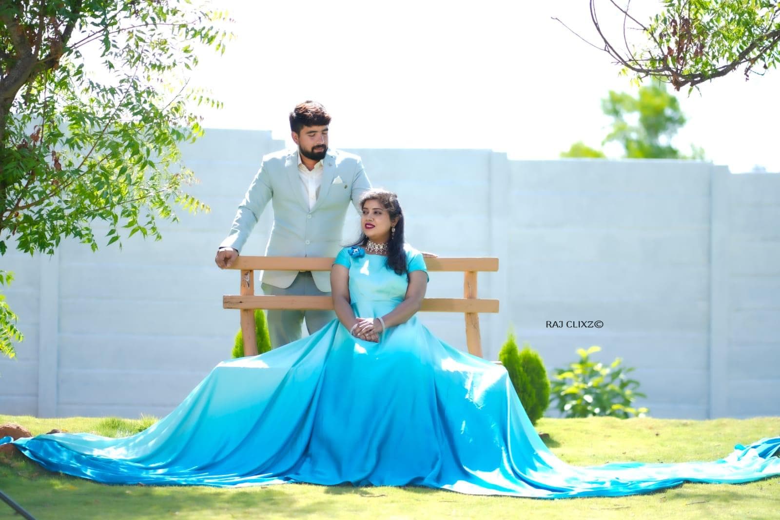A couple in blue on the lawn by a wooden bench
